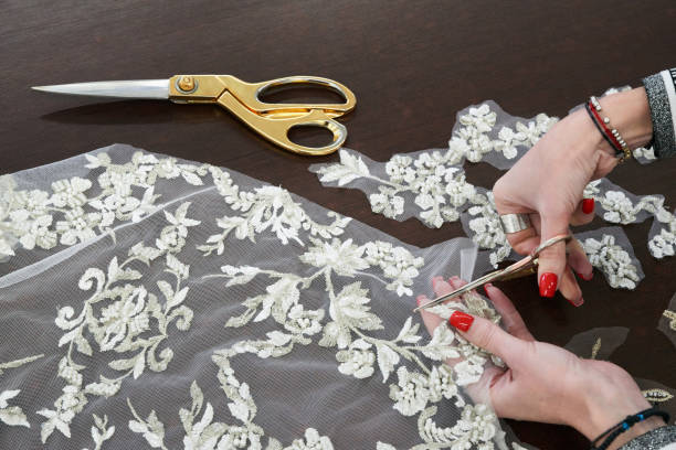 dressmaker cutting lace fabric for wedding dress decoration